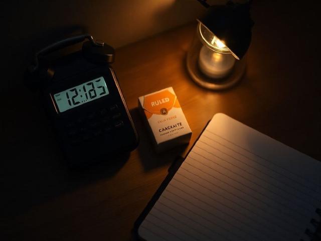 Phone alarm beside a cigarette pack and a ruled notebook